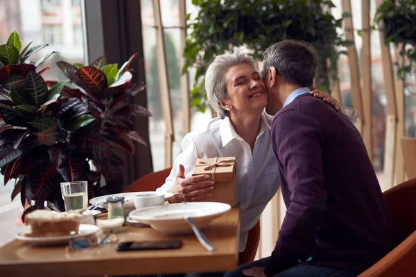Елегантна жінка вдячно цілує чоловіка за подарунок — стокове фото