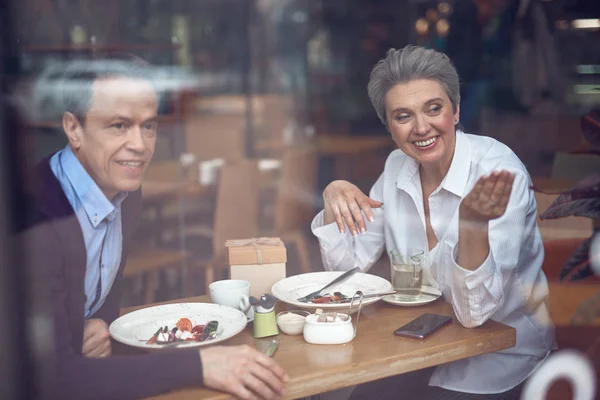 Happy couple looking on smth outside of cafe — Stock Photo, Image