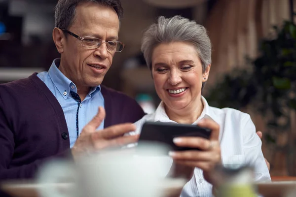Aged couple look with interest in mobile phone — Stock Photo, Image