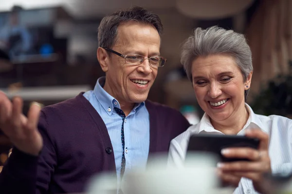 Åldrad par diskuterar ngt i mobiltelefon — Stockfoto