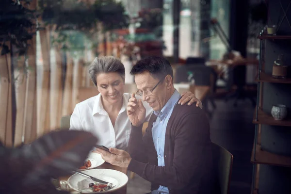 Elegant par ser med intresse för mobiltelefon — Stockfoto