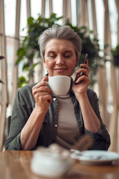 Rahat yaşlı kadın kafede telefonda konuşurken