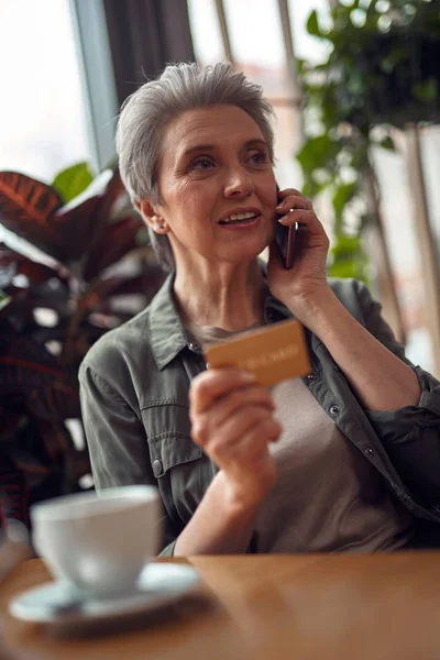 Kafede telefonla konuşan dikkatli yaşlı kadın — Stok fotoğraf
