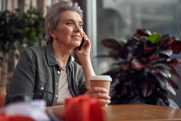 Relajada mujer sonriente hablando por teléfono en la cafetería — Foto de Stock