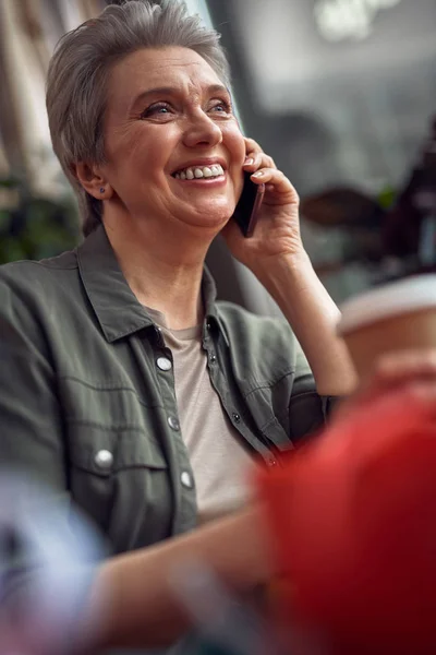 Щаслива усміхнена жінка розмовляє по телефону в кафе — стокове фото