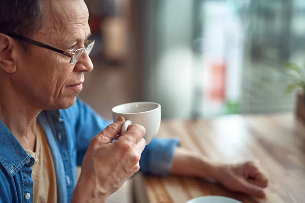 Relajado anciano sentado en la cafetería con café — Foto de Stock