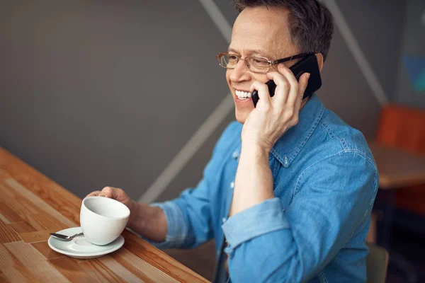 Happy aged man talking by mobile phone in cafe — Stock Photo, Image