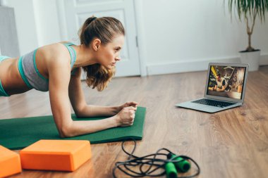 Young lady doing plank practice at home