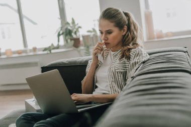 Grip olan yorgun kadın dizüstü bilgisayar ile kanepede oturuyor