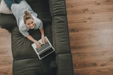 Neşeli kadın dizüstü bilgisayar ile kanepede döşeme