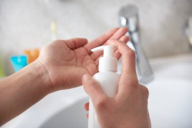 Young lady pouring body lotion on hand