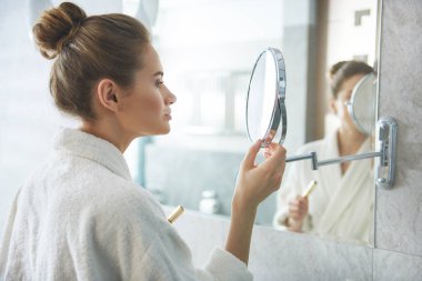 Bayan küçük yuvarlak vanity cam ayna bakıyor