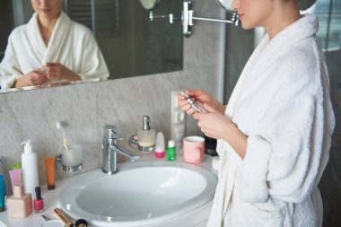 Young lady holding bottle of perfume in hand