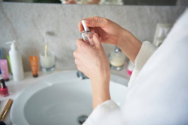 Genç bayanın elinde parfüm şişesi yakın