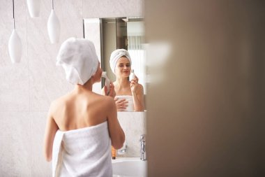 Fırçayla yüzünü temizleyen genç, güzel bayan.