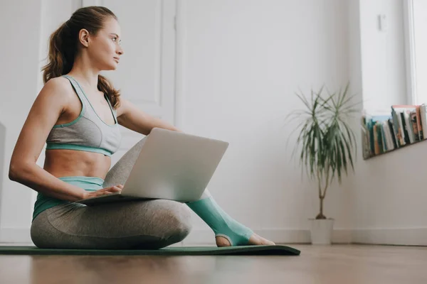 Balanced woman sitting with laptop on bending leg