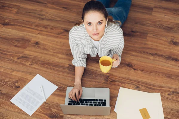 Ung kvinna som arbetar på golvet med bärbar dator — Stockfoto