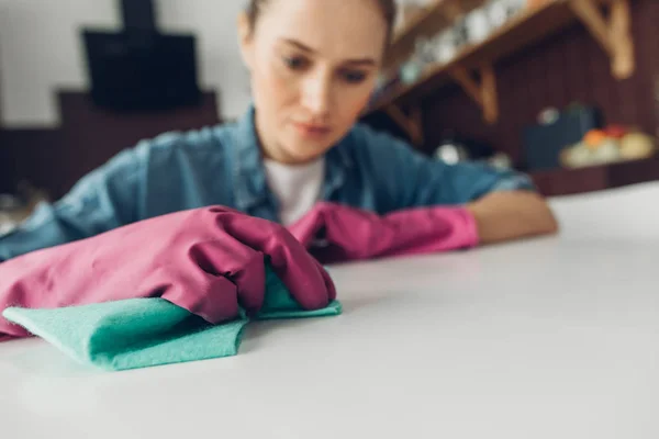 Mujer limpiando cuidadosamente la superficie de la mesa en casa — Foto de Stock