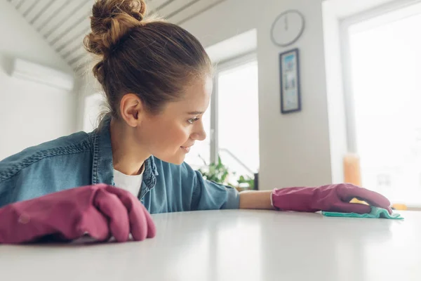 Mujer limpia cuidadosamente de la superficie de la mesa en casa — Foto de Stock