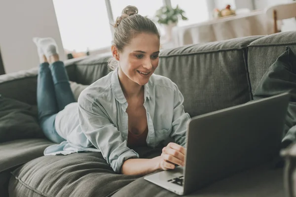 Mutlu kadın dizüstü bilgisayar ile kanepede döşeme — Stok fotoğraf