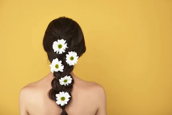 Lato posteriore donna graziosa con camomille in capelli — Foto Stock