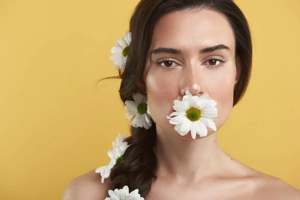 Jong brunette vrouw holding camomile in mond — Stockfoto