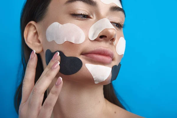 Mujer joven tocando sus parches cosméticos en la cara —  Fotos de Stock