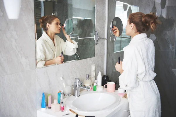 Молодая леди делает утренний макияж в ванной — стоковое фото