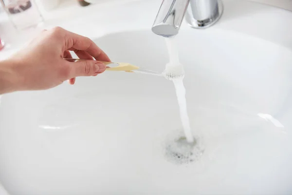 Dame wäscht Zahnbürste mit Paste mit Wasser — Stockfoto