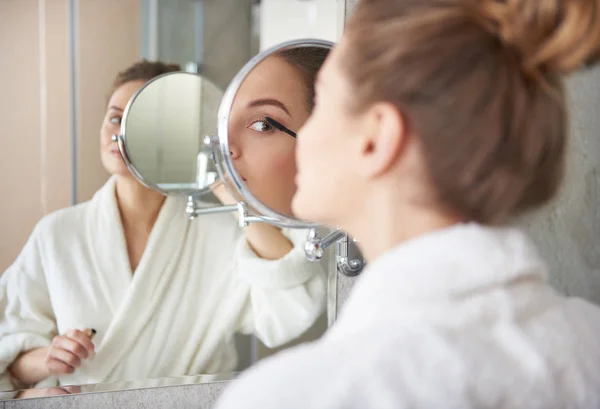 Back side of young lady putting on mascara — Stock Photo, Image