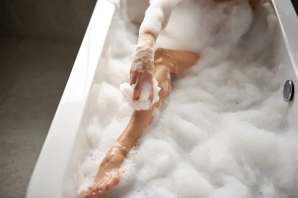 Top angle of lady washing legs by pouf in bath — Stock Photo, Image