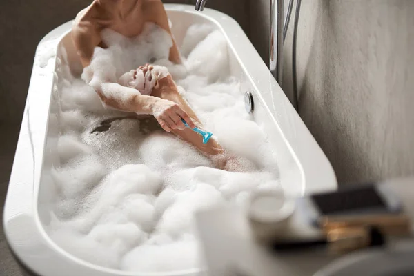 Обрізана голова леді гоління ноги в пінопластовій ванні — стокове фото