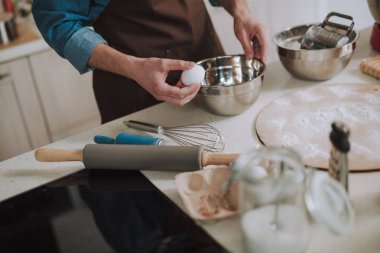 Metal kase yakınında bir yumurta tutan el