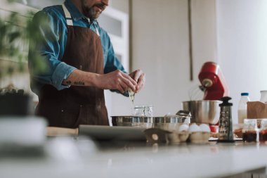 Yemek pişirirken kaseye yumurta döken adamın yakın çekim