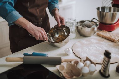 Yemek yaparken çırpma teli ile yumurta döven adamın elleri