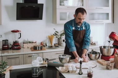 Hamur yoğururken ciddi görünümlü sakallı adam