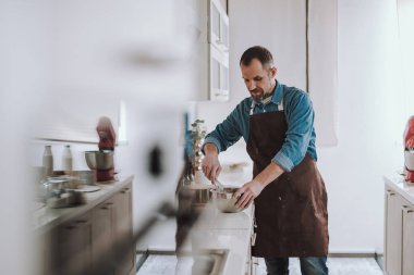 Konsantre sakallı adam tezgahın üzerinde yumurta çırpıyor
