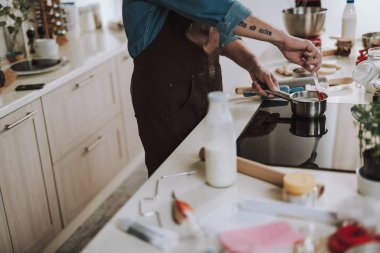Adam mutfakta ayakta ve tencereiçine spatula koyarak