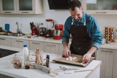 Çarşaf tavaya pasta koyarken gülümseyen neşeli adam