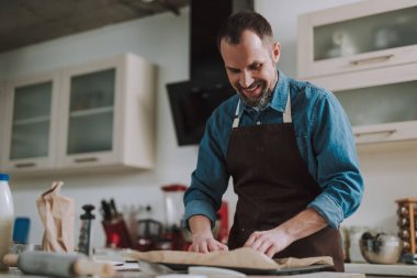 Mutlu adam gülümseyerek ve pişirme kağıdı bakarak