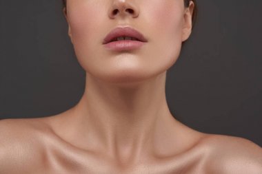 Gri arka plan aleyhine duran mükemmel bir cilde sahip güzel genç kadın