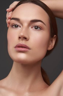 Doğal makyaj başının üzerinde el tutan Büyüleyici genç kadın