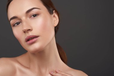 Gri arka plan aleyhine poz doğal makyaj ile Büyüleyici genç kadın