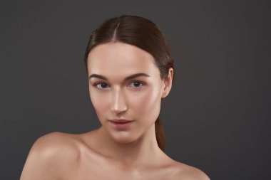 Gri arka plan aleyhine poz doğal makyaj ile güzel genç kadın