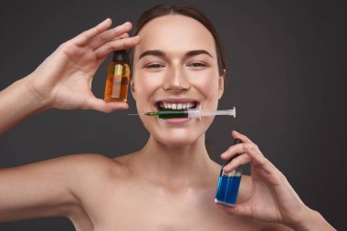 Çıplak omuzlu ve vitamin serumları gösteren büyüleyici genç kadın