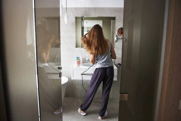 Giovane signora asciugare i capelli da asciugacapelli in bagno — Foto Stock