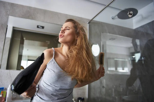 Šťastná dáma předstírá, že zpívá pomocí vysoušeče — Stock fotografie