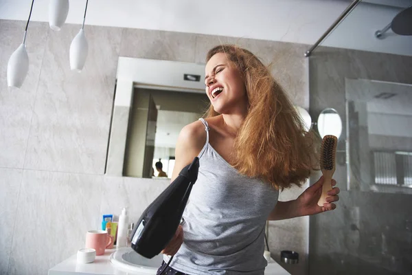Mladá šťastná dáma zpívá při sušení vlasů — Stock fotografie