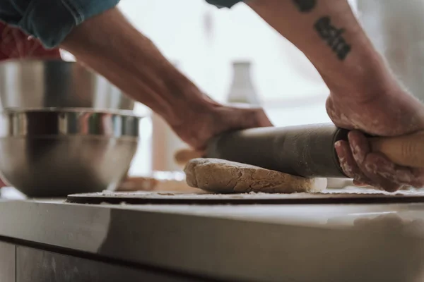 Nahaufnahme von Händen, die Teig auf dem Tisch rollen — Stockfoto