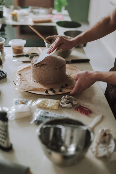 Tavolo da cucina con torta alla panna e pasticceria lisciandola — Foto Stock